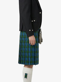 Person wearing a black jacket and green plaid kilt on a white background