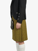 Person wearing a black blazer and yellow plaid kilt on a white background