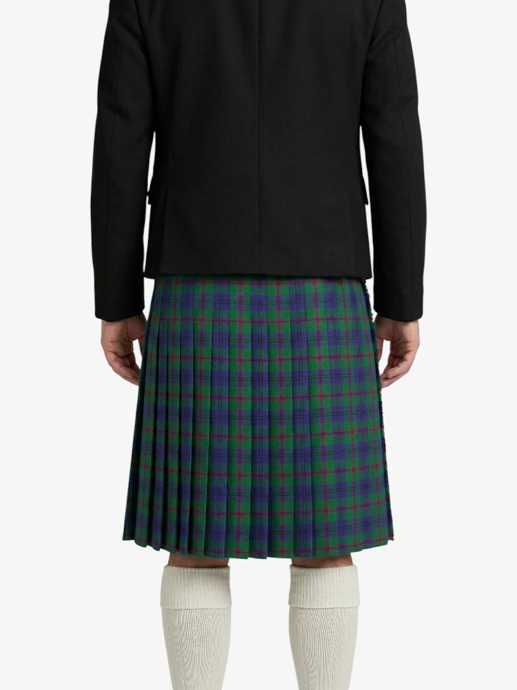 Person wearing a black jacket and green plaid kilt on a white background