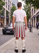 A man viewed from behind wearing a white t-shirt and a light gray kilt with bold red pleats, standing on a city sidewalk next to a street with cars and trees.