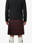 Person wearing a black jacket and red plaid kilt on a white background