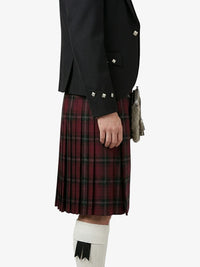 Person wearing a black jacket and red plaid kilt on a white background