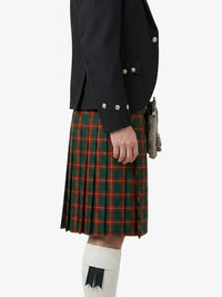 Person wearing a black jacket and green plaid kilt on a white background
