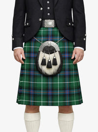 Person wearing a traditional Scottish kilt with a tartan pattern on a white background