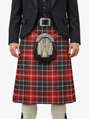Person wearing a red tartan kilt with a black jacket and white shirt on a white background