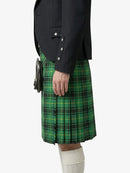 Person wearing a green plaid kilt with a dark jacket on a white background