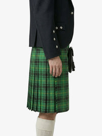 Person wearing a green plaid kilt with a dark jacket on a white background