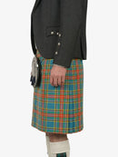 Person wearing a gray jacket and a colorful plaid kilt on a white background