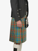 Person wearing a dark gray jacket and a colorful plaid kilt on a white background