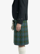 Person wearing a dark jacket and green plaid kilt on a white background