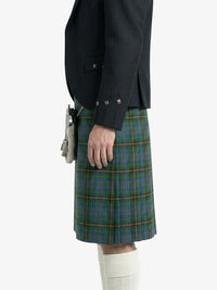 Person wearing a dark jacket and green plaid kilt on a white background