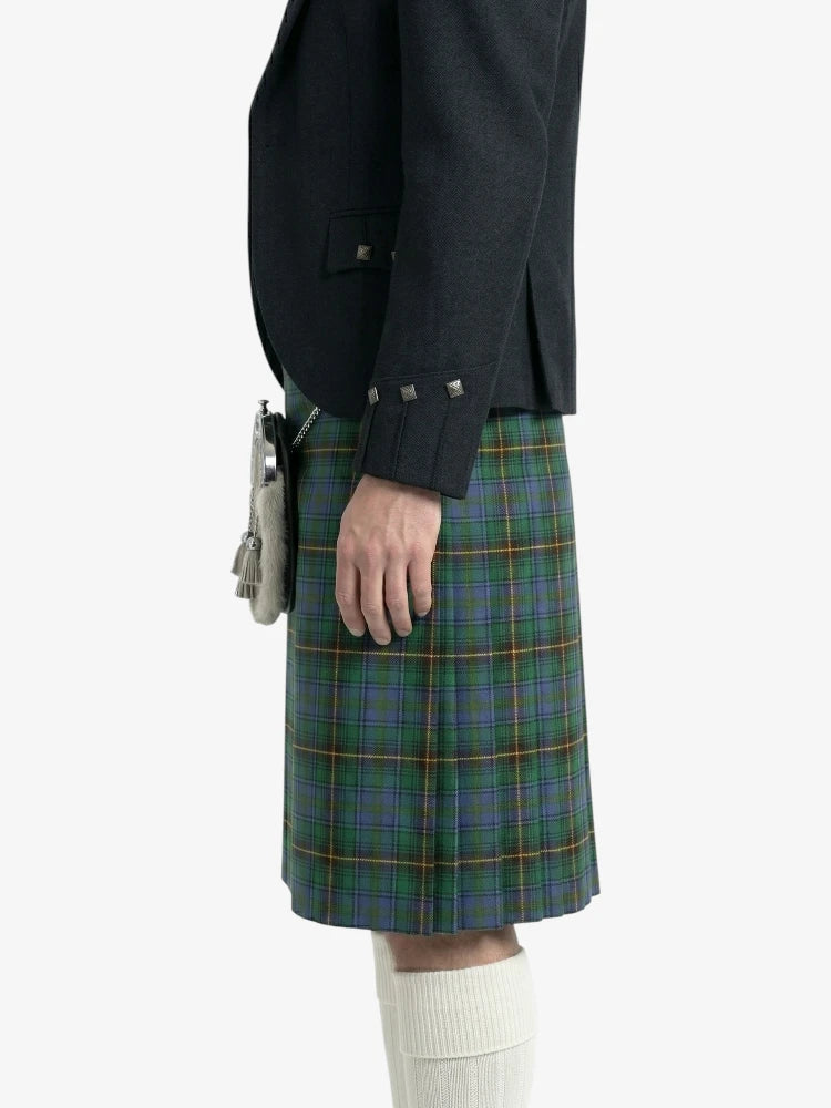 Person wearing a dark jacket and green plaid kilt on a white background