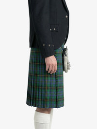 Person wearing a black jacket and green plaid kilt on a white background