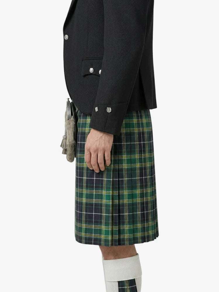 Person wearing a black blazer and green plaid kilt on a white background
