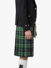 Person wearing a black jacket and green plaid kilt on a white background