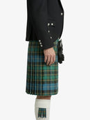 Person wearing a black jacket and green plaid kilt on a white background