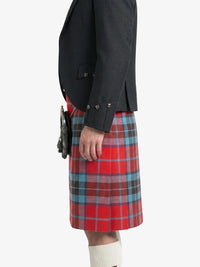Person wearing a dark jacket and red plaid kilt on a white background