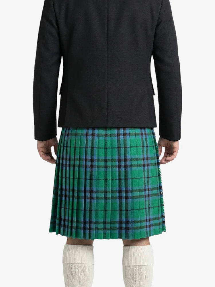 Person wearing a green plaid kilt with a black jacket on a white background