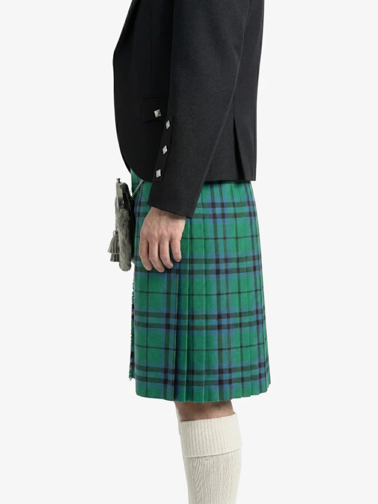 Person wearing a black jacket and green plaid kilt on a white background