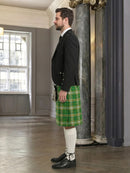 Man wearing a green plaid kilt with a black jacket in an elegant room.