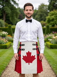 A man standing in a formal garden wearing a white shirt, black bow tie, and a red and white kilt with a large red maple leaf design on the front.