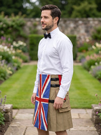 A man standing in a garden wearing a white dress shirt, black bow tie, and a tan kilt with a Union Jack flag design on the front panel.