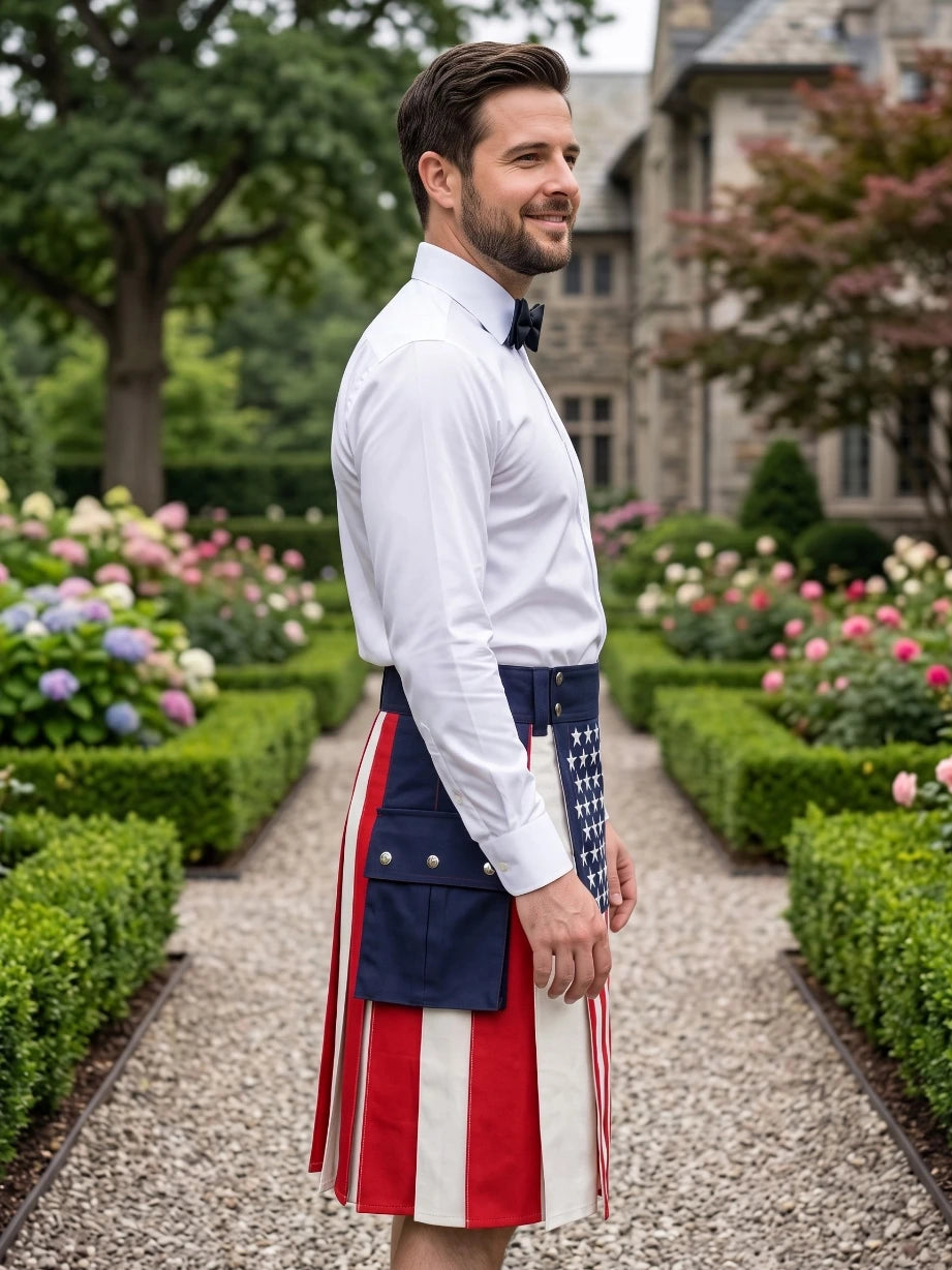 A man wearing a patriotic kilt with red and white stripes and a blue section with white stars, paired with a white dress shirt and black bow tie, standing in a garden pathway.