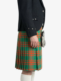 Person wearing a black coat and green plaid kilt on a white background