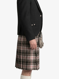 Person wearing a black jacket and plaid kilt on a white background