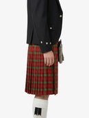 Person wearing a black jacket and red plaid kilt on a white background