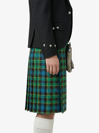 Person wearing a black jacket and green plaid kilt on a white background