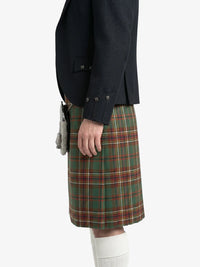 Person wearing a dark jacket and green plaid kilt on a white background