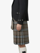 Person wearing a black blazer and plaid kilt on a white background