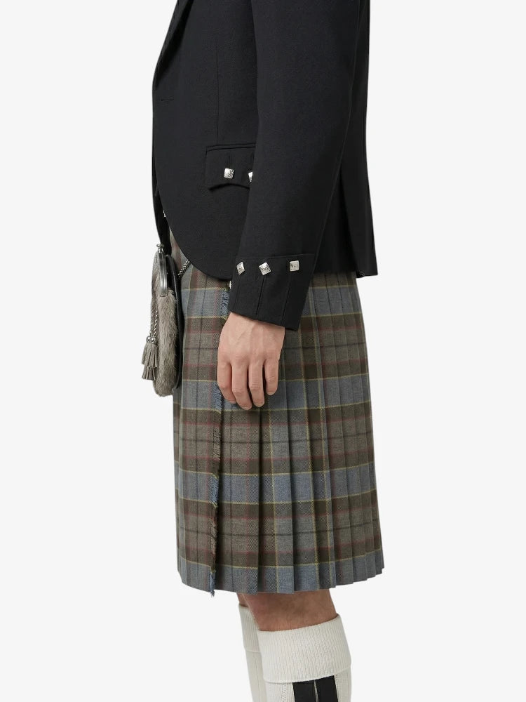 Person wearing a black blazer and plaid kilt on a white background