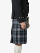 Person wearing a black jacket and plaid kilt on a white background