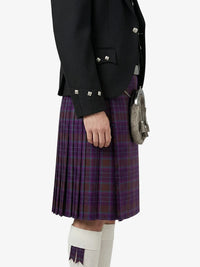 Person wearing a black jacket and purple plaid kilt on a white background
