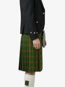 Person wearing a green plaid kilt with a black jacket on a white background