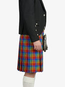 Person wearing a black blazer and colorful plaid kilt on a white background