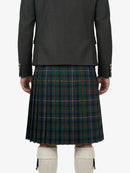 Person wearing a dark gray jacket and green plaid kilt on a white background