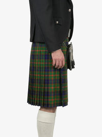 Person wearing a dark jacket and green plaid kilt on a white background