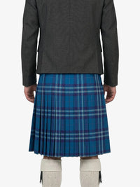Person wearing a gray jacket and blue plaid kilt on a white background