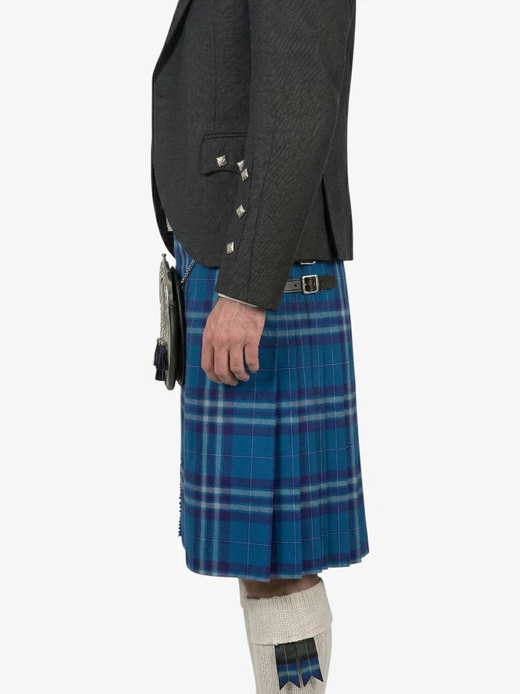 Person wearing a dark gray jacket and blue plaid kilt on a white background