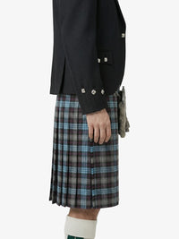 Person wearing a black jacket and plaid kilt on a white background