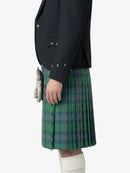Person wearing a dark jacket and green plaid kilt on a white background