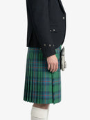 Person wearing a green plaid kilt with a dark jacket on a white background