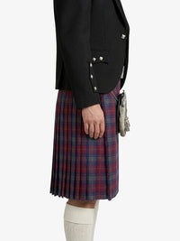 Person wearing a black blazer and red plaid kilt on a white background