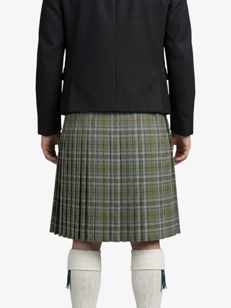 Person wearing a black jacket and green plaid kilt on a white background