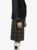 Person wearing a black jacket and plaid kilt on a white background