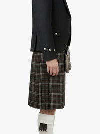 Person wearing a black jacket and plaid kilt on a white background