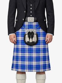 Person wearing a blue plaid kilt with a black jacket and white socks on a white background